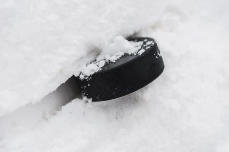 hockey puck lies on the snow macro