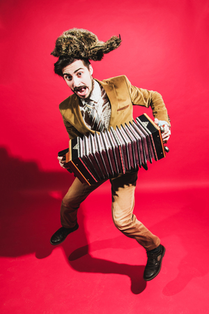 positive man with accordion posing in studioの写真素材