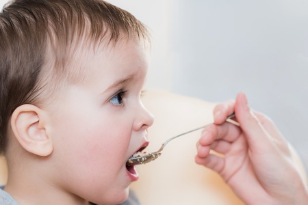Mom feeds the child buckwheat porridge in the kitchenの写真素材
