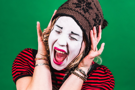 cheerful mime girl posing and grimacing in photo studioの写真素材