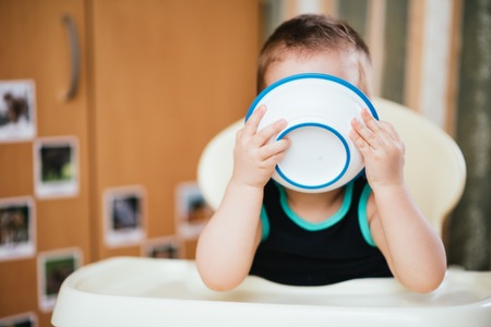Kid plays in the kitchen with dishesの写真素材
