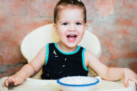 baby in the kitchen eating vermicelli with milk