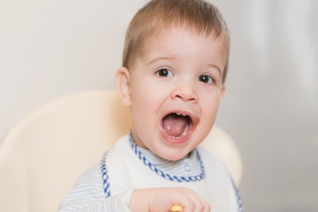 child in the kitchen eating fruit pureeの写真素材