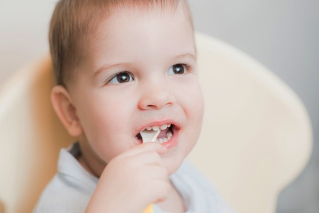 child in the kitchen eating fruit pureeの写真素材