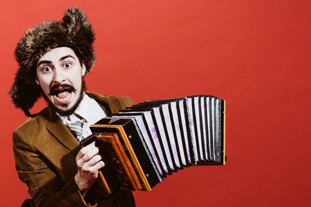 positive man with accordion posing in studioの写真素材