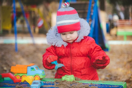 the kid plays cars in the sandbox on the streetの写真素材