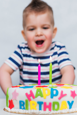 a little child blows a candle on a cake on his birthdayの写真素材