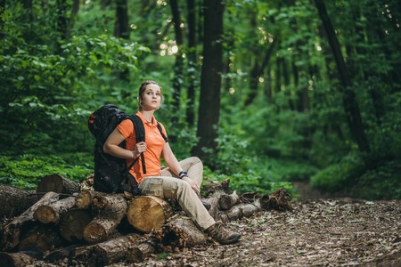 girl with a backpack relax in the woods on logs