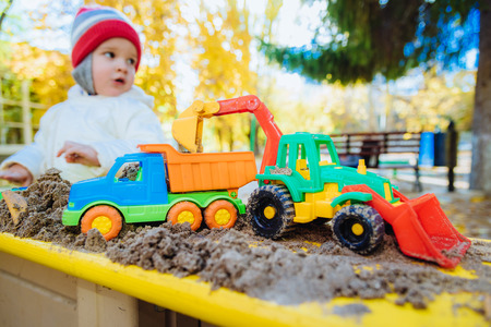 the kid plays cars in the sandbox on the streetの写真素材