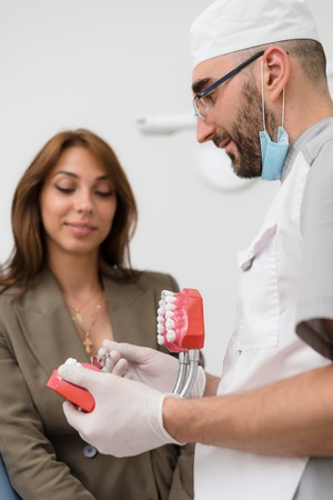 the orthodontist shows the girl on the example of a human jaw, how teeth are arranged in the mouthの写真素材