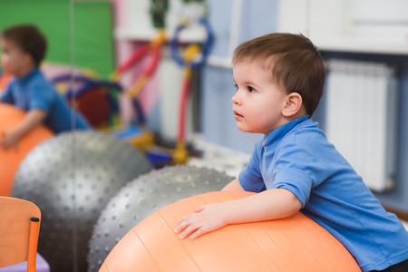 little child playing with a fitball in the gymの写真素材
