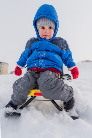 little boy rides a snow scooter in winterの写真素材