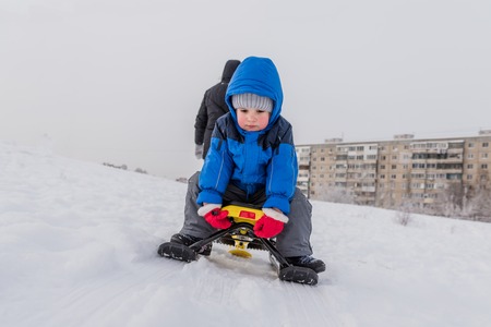 woman carries her son on a snow scooter in winterの写真素材