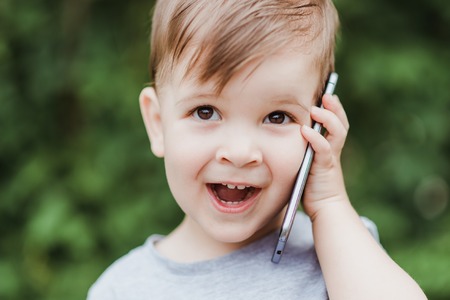 little boy speaks on the smartphone in the parkの写真素材
