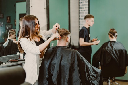 girl hairdresser cuts scissors bearded man in the salonの写真素材