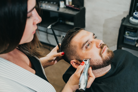 woman hairdresser does the hair to a brutal man in the salonの写真素材