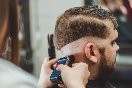 woman hairdresser does the hair to a brutal man in the salonの写真素材
