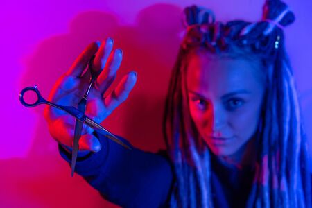 woman hairdresser with dreadlocks holding scissors in hand close-upの写真素材
