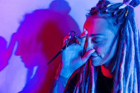 woman hairdresser with dreadlocks holding scissors in hand close-upの写真素材
