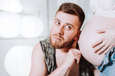 The husband listens to the baby in the wife s stomach with his ear.