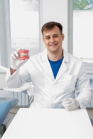 the doctor shows how the system of braces on teeth is arranged