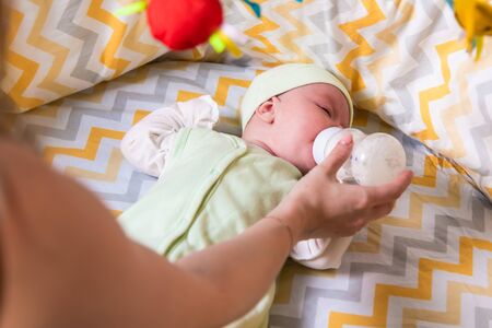 mother gives a newborn baby milk from a bottle