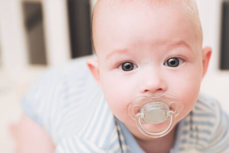 The infant lies in a bed on his belly.