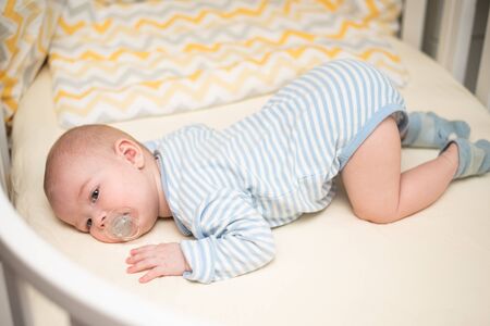 The toddler lies in a bed on his stromach.