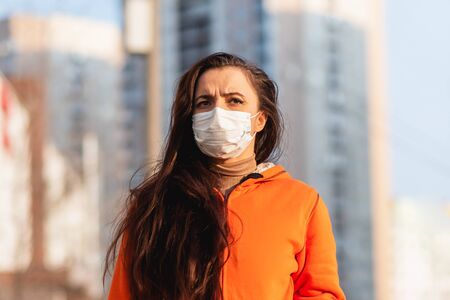 Portrait of a scared girl in a medical mask on the street during the coronavirus and Covid-19 pandemicの写真素材