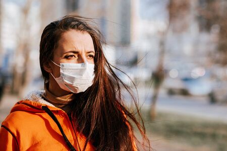Portrait of a scared girl in a medical mask on the street during the coronavirus and Covid-19 pandemicの写真素材