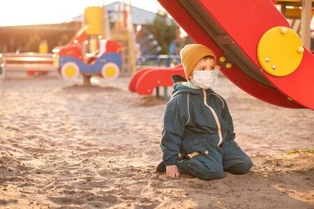 A boy in a protective mask plays in the playground during the coronavirus and Covid pandemic - 19