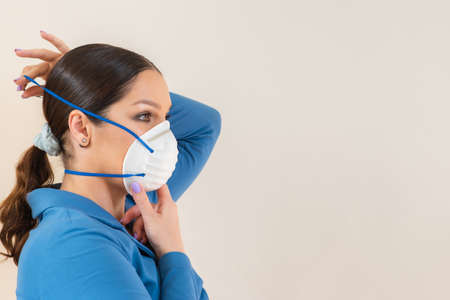 Beautiful woman puts a medical mask on her face on the nature. Coronavirus and Covid-19 Protectionの写真素材