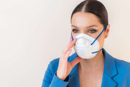 Beautiful woman puts a medical mask on her face on the nature. Coronavirus and Covid-19 Protectionの写真素材