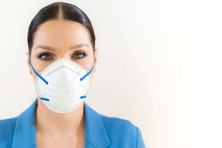 Beautiful woman puts a medical mask on her face on the nature. Coronavirus and Covid-19 Protectionの写真素材