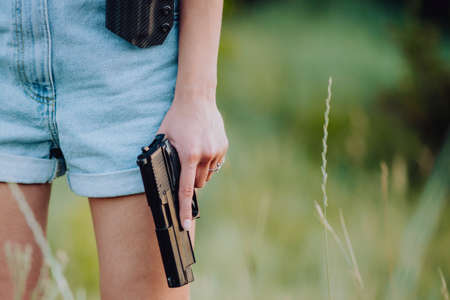 girl in denim shorts and with a gun in his hand posing in the field.の写真素材