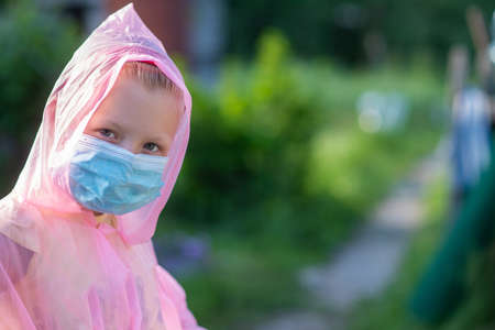 Portrait of a child in protective clothing and a medical mask on the street in summer. Prevention against coronavirus and Covid-19 during a pandemicの写真素材
