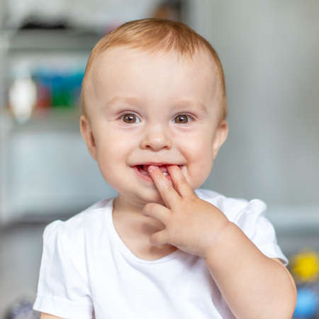baby laughs and sucks toes while sitting on the floor