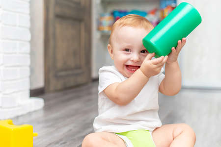 Happy laughing toddler playing with a toy sitting on the floor at homeの写真素材