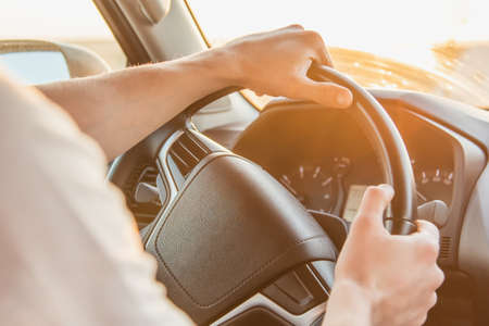 A man sits behind the wheel of his car on a sunny day