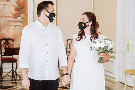 Wedding during the coronavirus epidemic. Bride and groom in protective medical masks. Marrieds and Covid-19 pandemic.の写真素材