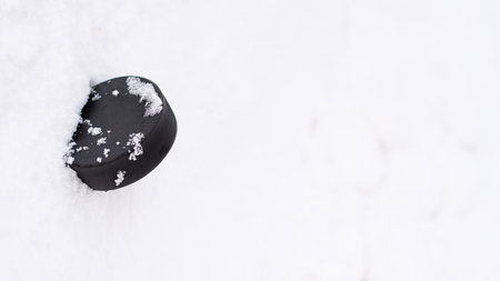 black hockey puck lies on ice at stadiumの写真素材