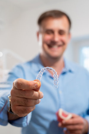 Dental care.Smiling dentist doctor holding aligners and braces in hand shows the difference between themの写真素材