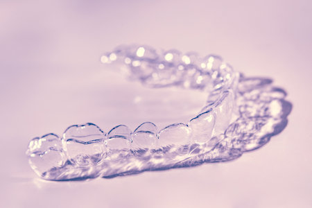 Invisible dental teeth brackets tooth aligners on pink background. Plastic braces dentistry retainers to straighten teeth.の写真素材