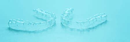 Invisible aligner teeth retainers on a turquoise background