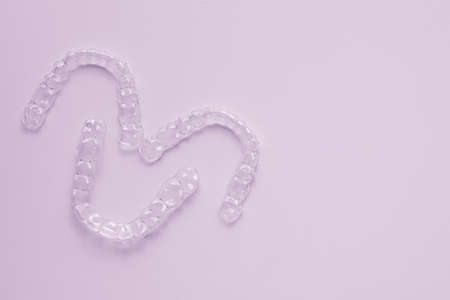 Invisible aligner teeth retainers on a pink background