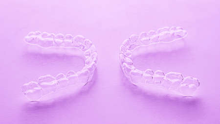 Invisible aligner teeth retainers on a pink background