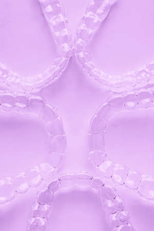 Invisible aligner teeth retainers on a pink background