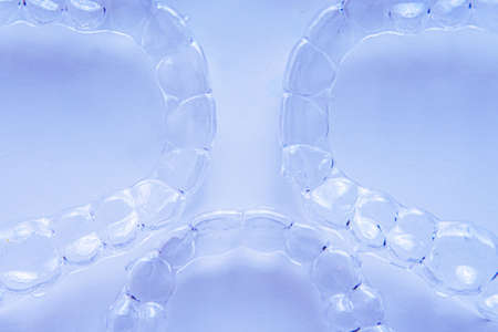 Invisible dental teeth brackets tooth aligners on blue background. Plastic braces dentistry...