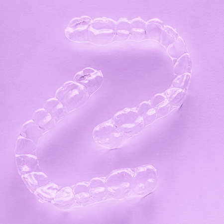 Invisible aligner teeth retainers on a pink background