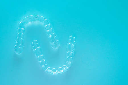 Invisible aligner teeth retainers on a turquoise background